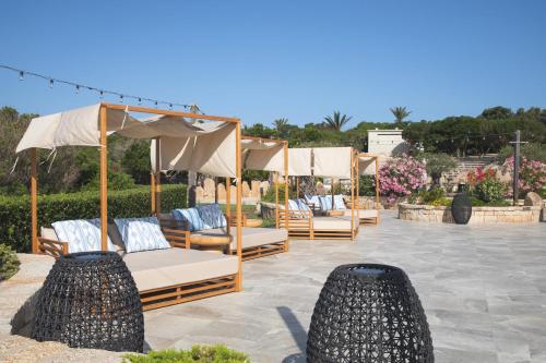a row of beds with umbrellas on a patio at Mangia's Sardinia Resort - NEW OPENING in Santa Teresa Gallura