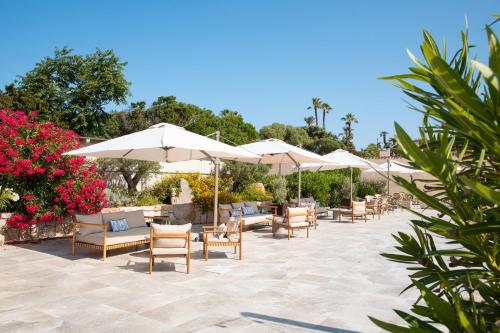 a patio with tables and chairs and umbrellas at Mangia's Sardinia Resort - NEW OPENING in Santa Teresa Gallura