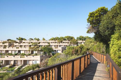 a wooden bridge over a walkway with white buildings at Mangia's Sardinia Resort - NEW OPENING in Santa Teresa Gallura