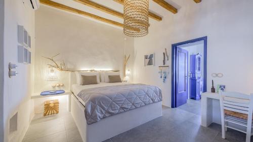 a white bedroom with a bed and a blue door at Mediterranea Blu in Triovasálos