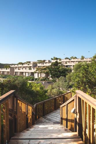 a wooden bridge with buildings in the background at Mangia's Sardinia Resort - NEW OPENING in Santa Teresa Gallura