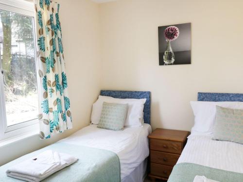 a bedroom with two beds and a window with a vase at Valley Lodge 2 in Callington
