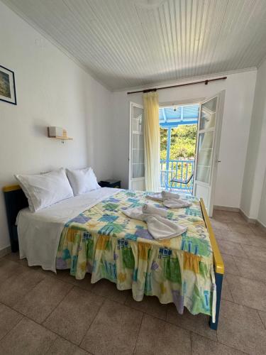 a bedroom with a bed and a balcony with a door at Galini Hellenic Hospitality in Patitiri