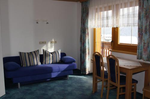 a living room with a blue couch and a table at Apart Gander in Kappl