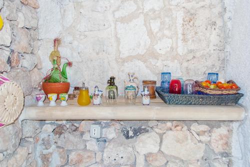 a shelf with glass figurines on a stone wall at Limonaia in Salento in Marittima