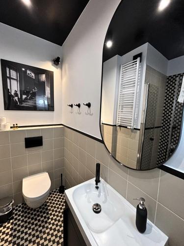 a bathroom with a sink and a toilet and a mirror at ROOSEVELTA RESIDENCE Apartments - przy OFF Piotrkowska in Łódź