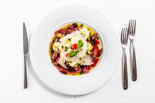 a bowl of food on a white plate with two forks at Albergo La Rocca in Brisighella