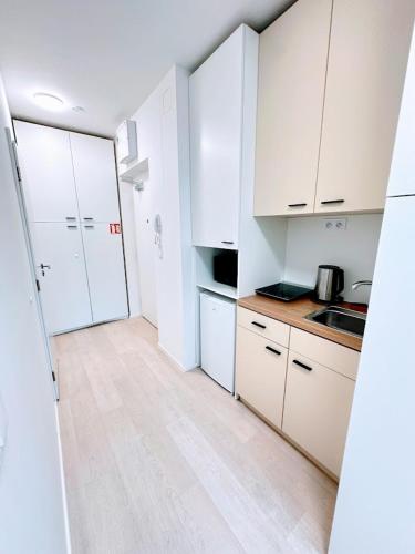 a kitchen with white cabinets and a wooden floor at Bella Apartments Brno in Brno
