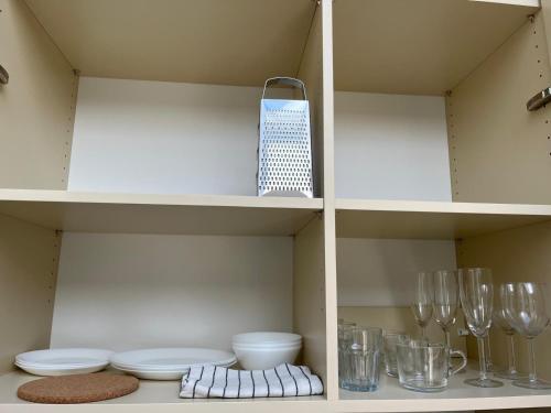 a kitchen with white shelves with glasses and dishes at Bella Apartments Brno in Brno