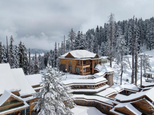 a lodge in the snow with snow covered trees at The Khyber Himalayan Resort & Spa in Gulmarg