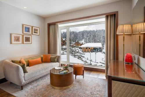 a living room with a couch and a large window at The Khyber Himalayan Resort & Spa in Gulmarg