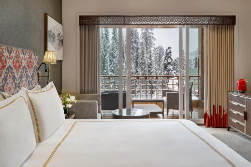 a hotel room with a bed and a balcony at The Khyber Himalayan Resort & Spa in Gulmarg