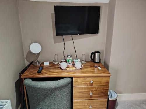 a wooden desk with a television and two cups on it at The Wheatsheaf in Salisbury