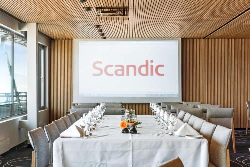 a conference room with a large screen with a board at Scandic Parken in Ålesund