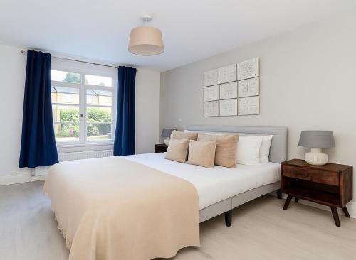 a bedroom with a large white bed with blue curtains at 1 Bed Flat near Syon Park in Isleworth