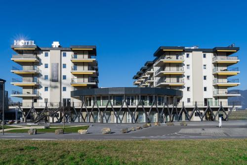 two tall white buildings in a parking lot at Alp Art Hotel Monthey in Collombey