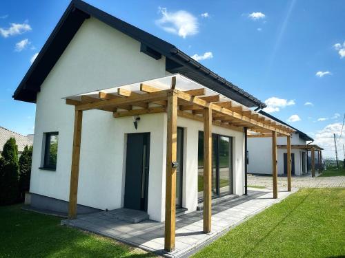 a small white house with a wooden roof at Domek Delux -komfortowe apartamenty, domki w Ojcowskim Parku Narodowym Z Jaccuzi in Wola Kalinowska