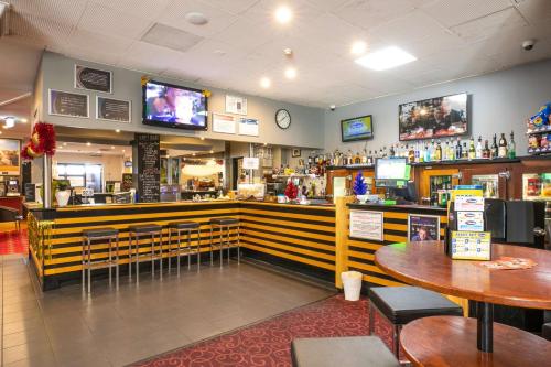 a restaurant with a bar with tables and televisions at Nightcap at Hendon Hotel in Adelaide