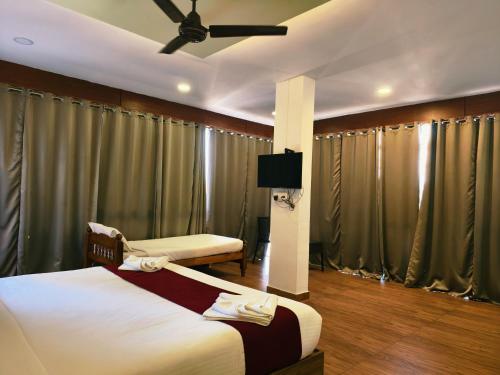 a hotel room with two beds and a flat screen tv at Udaya Resort in Palakkad