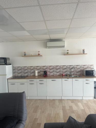 a kitchen with white cabinets and a brick wall at Le feuillu Bogny-sur-Meuse in Braux
