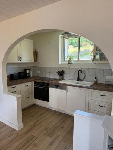 a kitchen with white cabinets and a sink and a window at La ferme de beau soleil Gîte et cabanes in Saint-Gilles-du-Mené