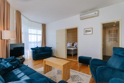 a living room with two blue couches and a table at Hestia Hotel Haapsalu SPA in Haapsalu