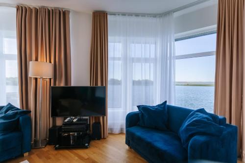 a living room with a blue couch and a large window at Hestia Hotel Haapsalu SPA in Haapsalu
