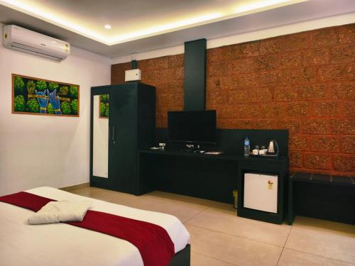 a bedroom with a bed and a desk with a television at Udaya Resort in Palakkad
