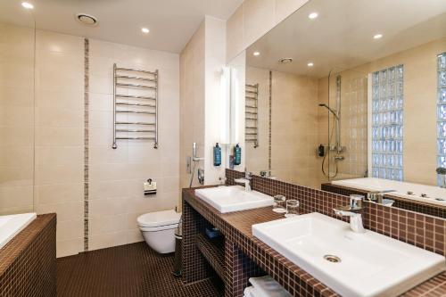 a bathroom with two sinks and a toilet and a mirror at Hestia Hotel Haapsalu SPA in Haapsalu