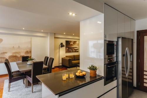 a kitchen and living room with a table and a refrigerator at Premium Apartment with Private Terrace & Garage in Porto