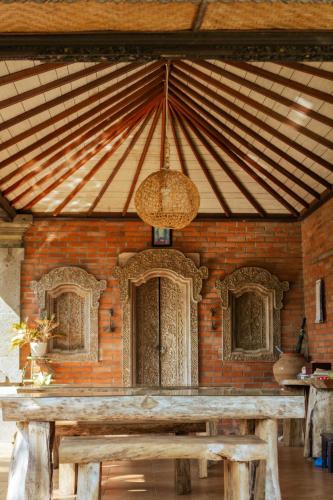 a wooden table in front of a brick wall at Mesari Cottage Guest House in Buleleng