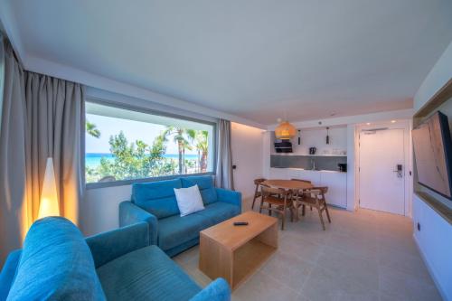 a living room with a blue couch and a table at Playa Esperanza Resort Affiliated by Meliá in Playa de Muro