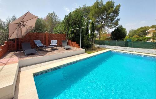 a swimming pool with two chairs and a table and an umbrella at Awesome Home In Bétera in Bétera