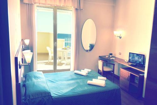 a room with a bed with a mirror and a balcony at Hotel Gala in Pesaro