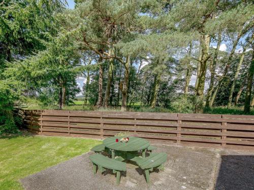 a picnic table and two green chairs in a yard at 2 Bed in Sanquhar 89403 in Sanquhar