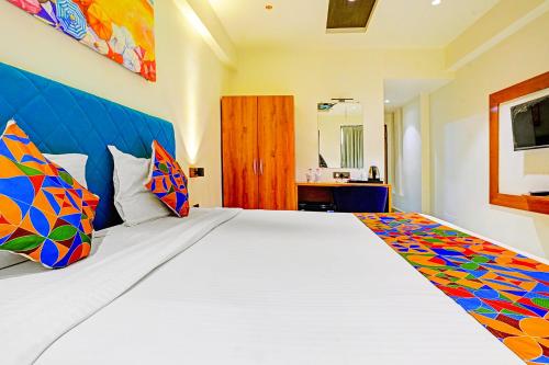 a bedroom with a large white bed with colorful pillows at FabHotel Siddharth Inn - Nr Siddharth Bunglows in Gandhinagar
