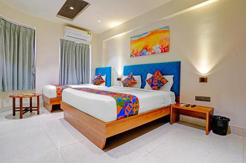 ein Schlafzimmer mit zwei Betten und einem Gemälde an der Wand in der Unterkunft FabHotel Siddharth Inn - Nr Siddharth Bunglows in Gandhinagar