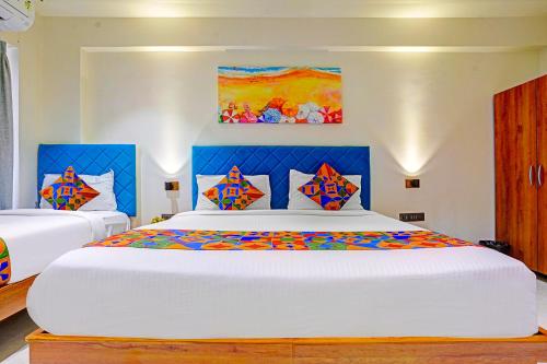 a bedroom with a large white bed with colorful pillows at FabHotel Siddharth Inn - Nr Siddharth Bunglows in Gandhinagar