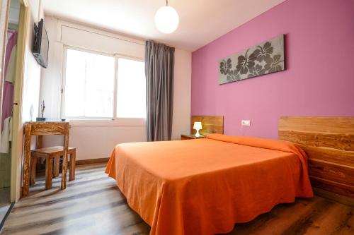 1 dormitorio con cama de color naranja y ventana en Hostal Ancora, en Lloret de Mar