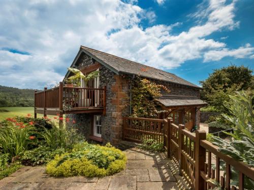 a stone house with a balcony and a wooden fence at 1 Bed in Coniston LCC37 in High Nibthwaite