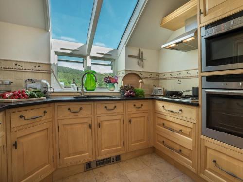 a kitchen with wooden cabinets and a large window at 1 Bed in Coniston LCC37 in High Nibthwaite