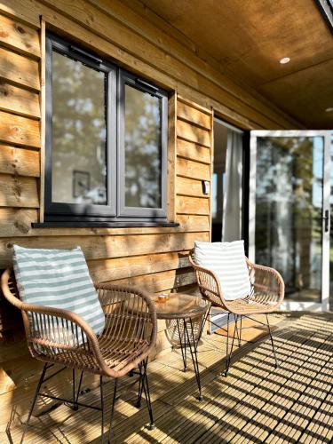 three chairs and a table on a porch at Lakeside Lodge- 'Swallow' in Bishampton