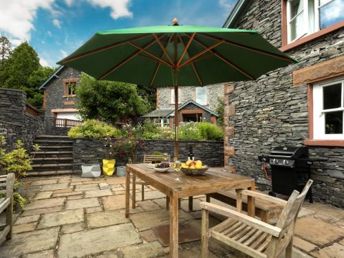a wooden table with a green umbrella on a patio at 1 Bed in Coniston LCC37 in High Nibthwaite