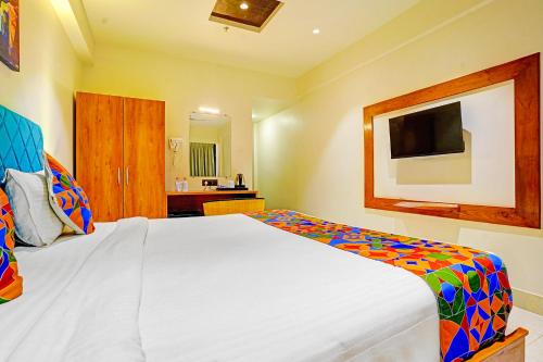 a bedroom with a large white bed and a television at FabHotel Siddharth Inn - Nr Siddharth Bunglows in Gandhinagar