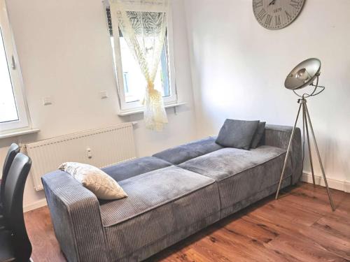 a couch in a living room with a clock on the wall at Ein Familie Haus in Zentrale Lage in Dreieich