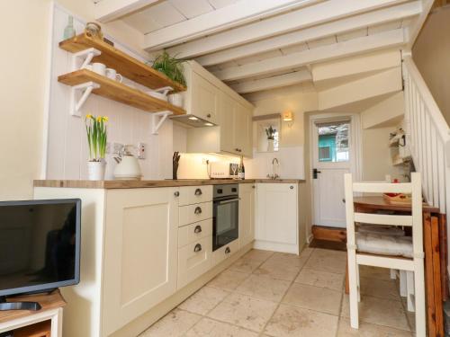 a small kitchen with white cabinets and a tv at Lavender Cottage in Askrigg