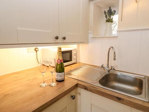 une cuisine avec une bouteille de vin et deux verres à vin dans l'établissement Lavender Cottage, à Askrigg