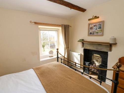 une chambre avec un lit et une cheminée dans l'établissement Lavender Cottage, à Askrigg
