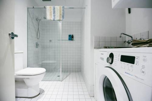 a bathroom with a washing machine and a toilet at Bent St Apartments in Adelaide
