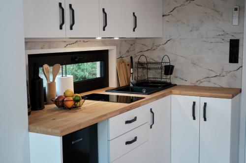a kitchen with white cabinets and a bowl of fruit on a counter at Villa Biesisko Przysłup Cisna in Cisna